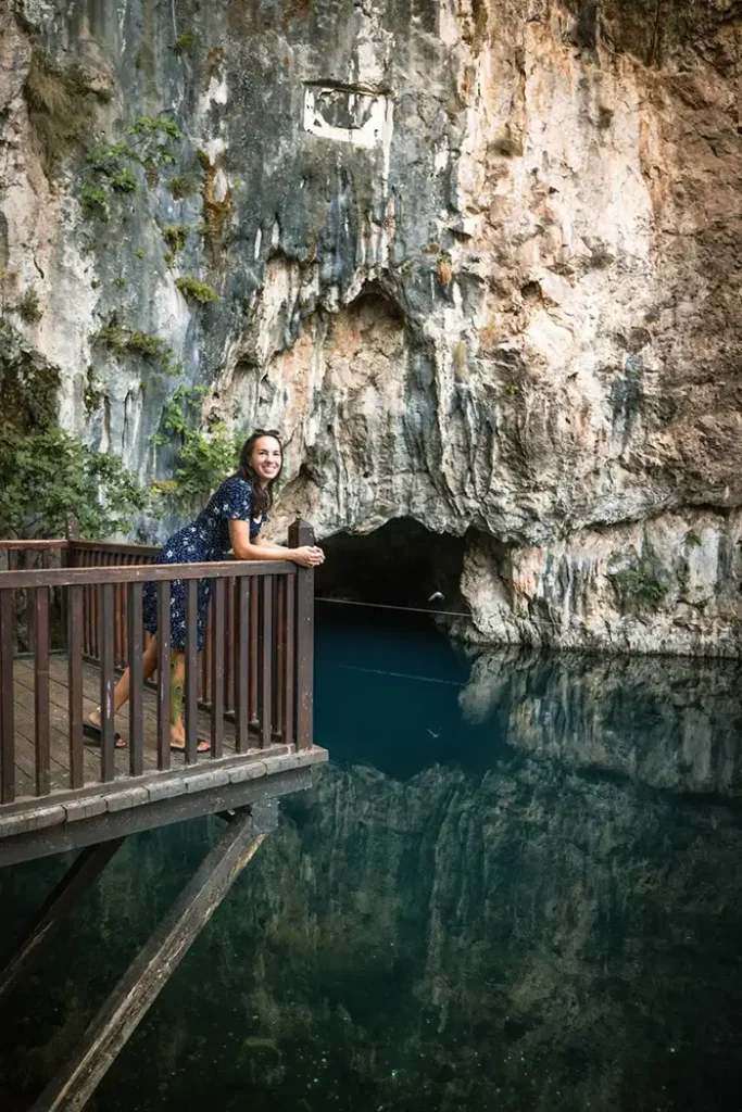 Eine Frau in einem blauen Kleid lacht frei vor glasklarem Wasser – Symbol für Leichtigkeit, Natürlichkeit und die persönliche Seite von morriña