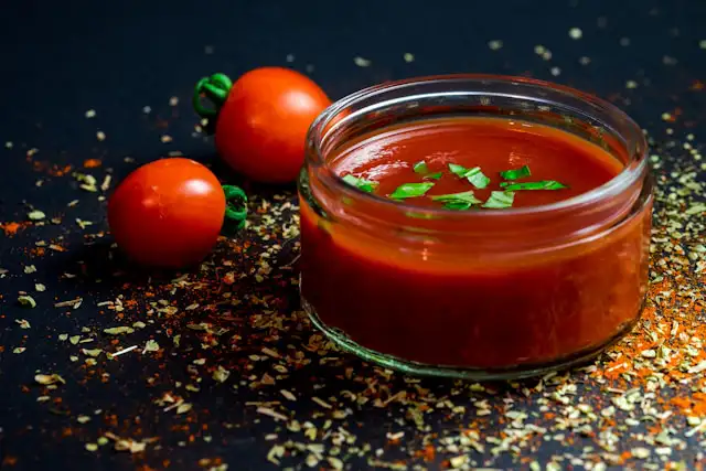 Ketchup selber machen – hausgemachter Ketchup im Schälchen mit frischen Kräutern